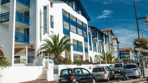Een hotel met meerdere verdiepingen, balkons en een helderblauwe lucht.