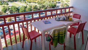 A balcony with a table, chairs, and a view of a body of water and buildings.