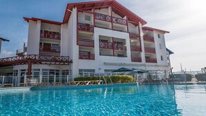 A multi-story hotel with balconies, a swimming pool, and outdoor seating.