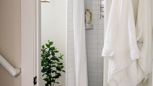 A bathroom with a shower, white towels, a potted plant, and a tiled floor. - King beds, central location, entire house. Perfect for family gathering! (Saint Paul)