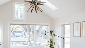 A spacious living room with a high ceiling, a wooden ceiling fan, large windows, a grey sofa, two wooden chairs, a coffee table, and a floor lamp. - King beds, central location, entire house. Perfect for family gathering! (Saint Paul)