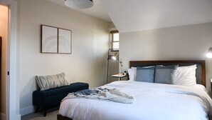 A bedroom with a large bed, a bedside table, a floor lamp, and a dark-colored bench. - King beds, central location, entire house. Perfect for family gathering! (Saint Paul)