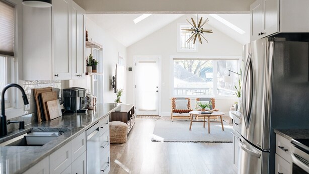 A modern kitchen with white cabinets, a stainless steel refrigerator, and a dining area with a wooden table and chairs. - King beds, central location, entire house. Perfect for family gathering! (Saint Paul)