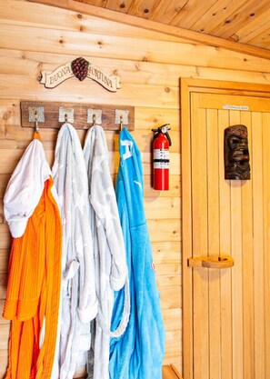 Eine Holzwand mit aufgehängten Handtüchern, einem Feuerlöscher und einer Holztür mit geschnitzt Gesicht.