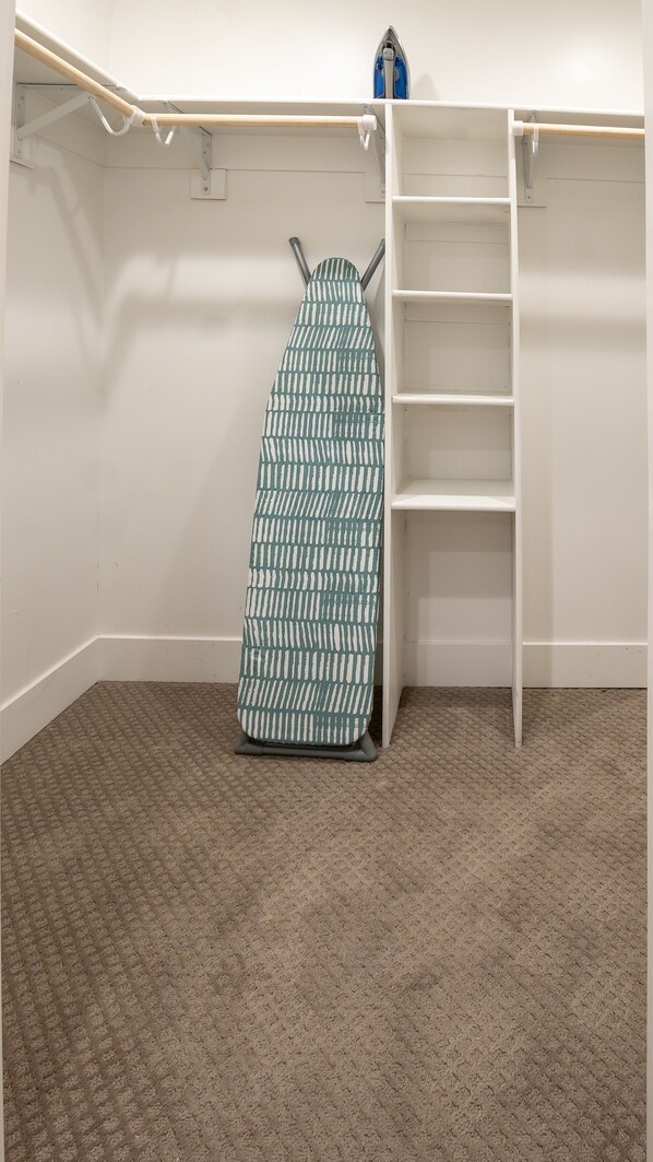 A room with a built-in ironing station, a wooden ironing board, and a white shelving unit. - Stylish Private Guest Suite, central to it all! (Phoenix)