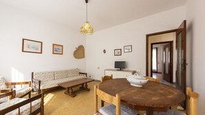 Ein Essbereich mit einem runden Holztisch, Stühlen, einer Couch und einem Fernseher.