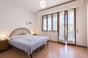 A bedroom with a bed, nightstands, a window with curtains, and a ceiling light.