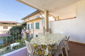 A balcony with a table and chairs, overlooking a residential area.