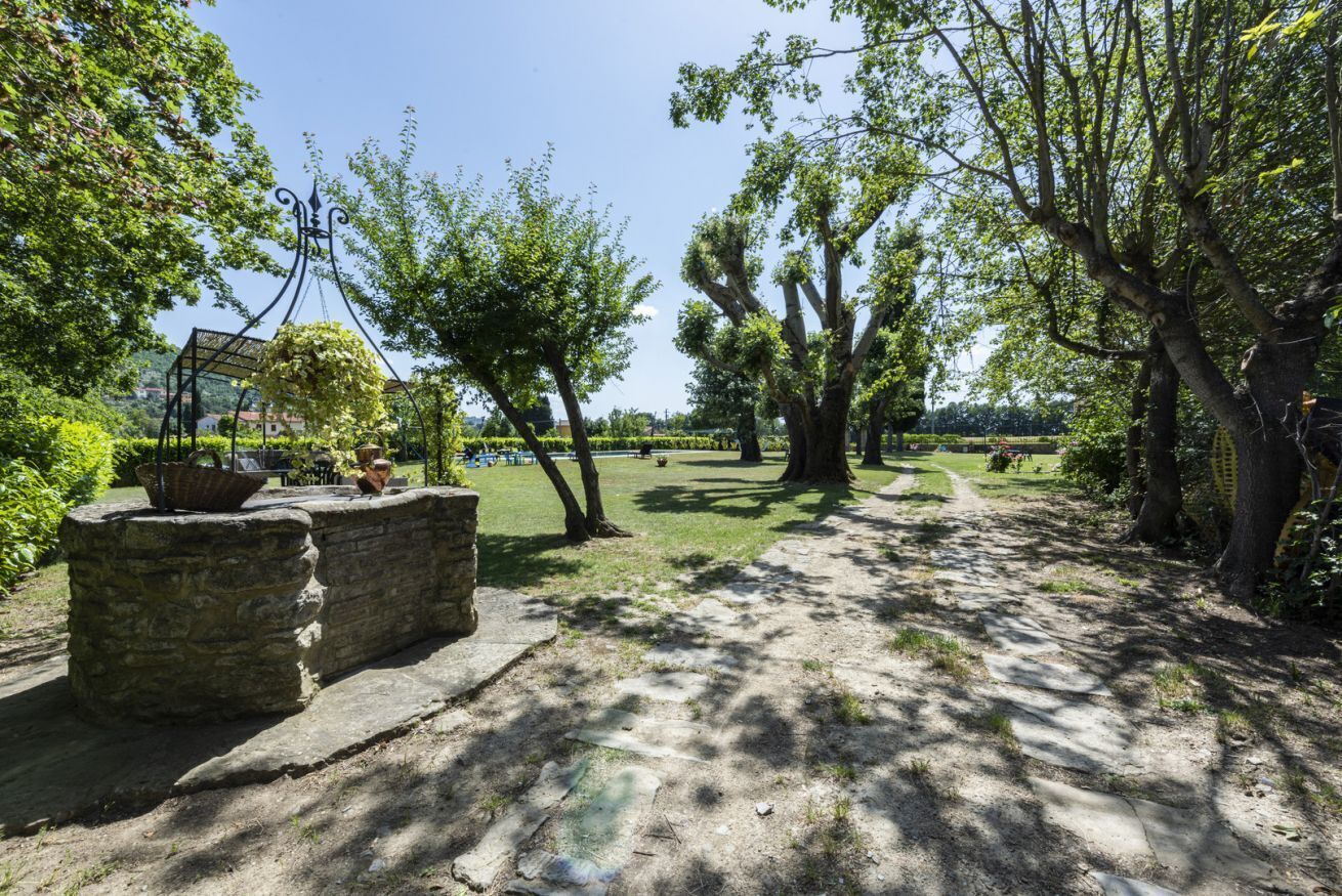 Un sentier aménagé dans un parc, avec des bancs en pierre, des arbres et un ciel dégagé.