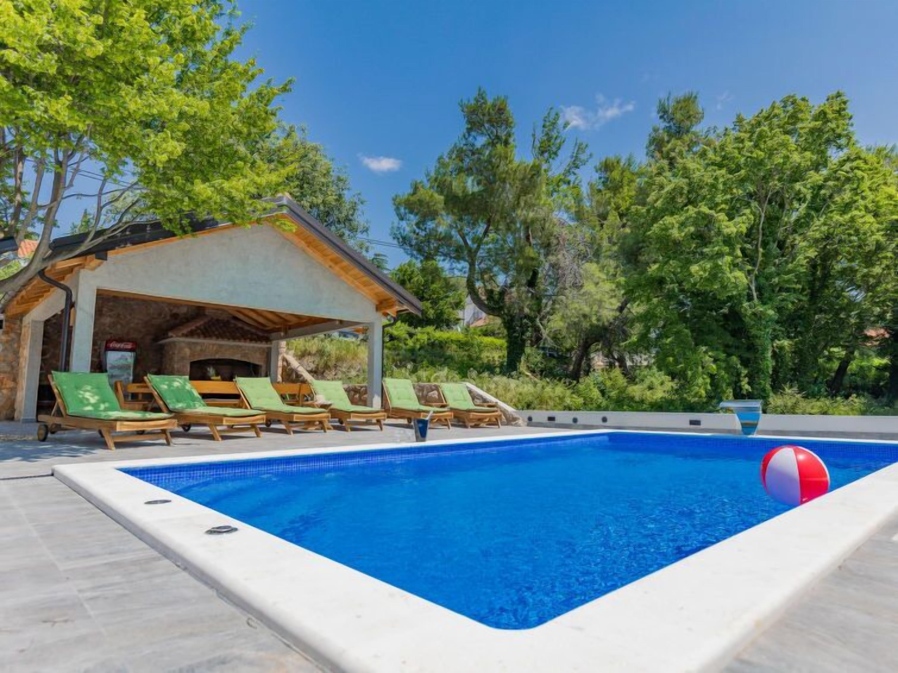 Une piscine avec des chaises longues et un espace de détente abrité.