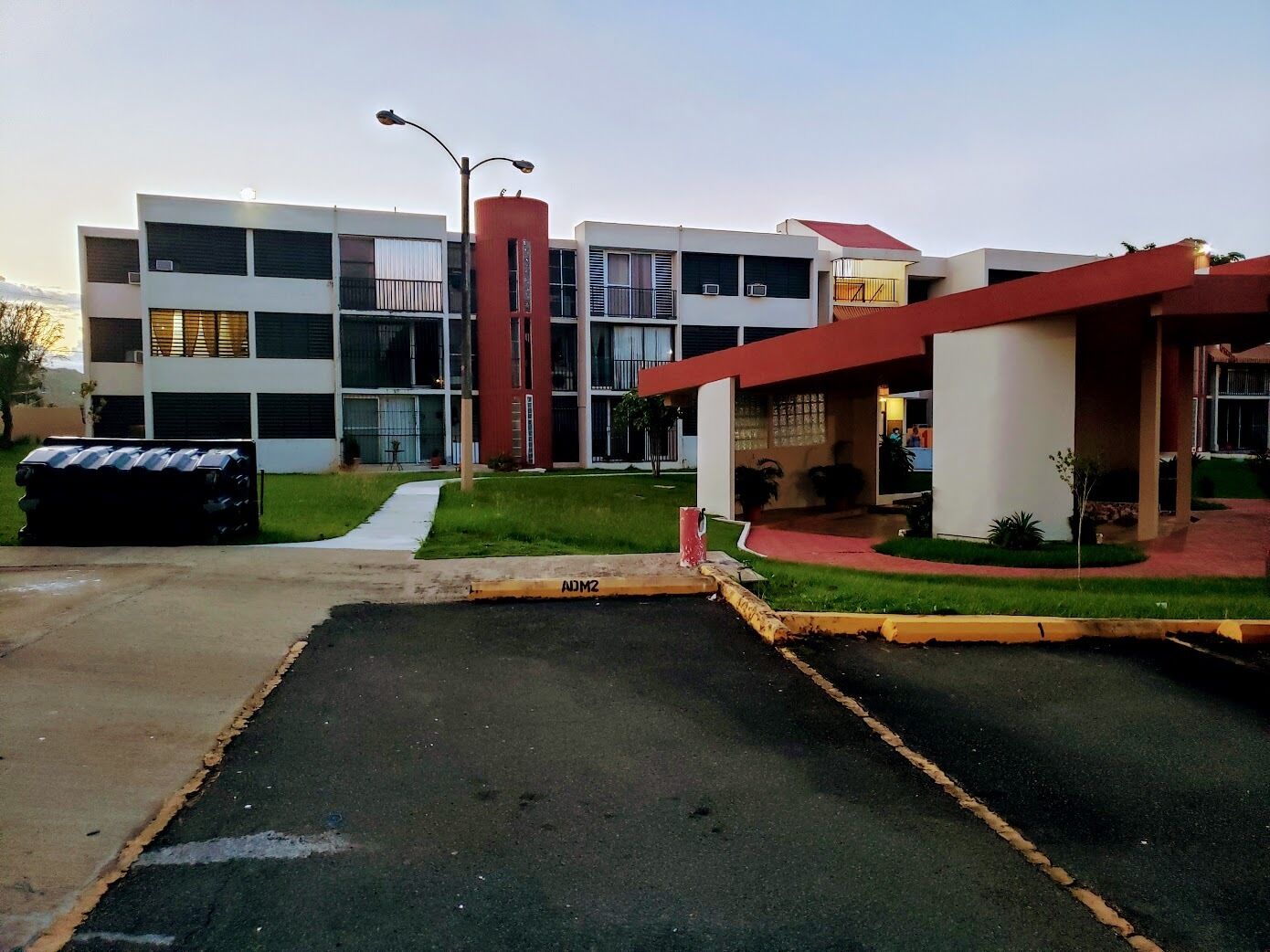 A modern building with a parking lot and a red structure.