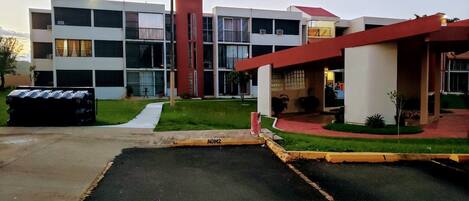A modern building with a parking lot and a red structure.