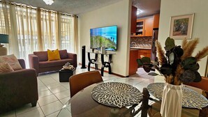 Ein Wohnzimmer mit Sofa, Couchtisch, Fernseher und Essbereich mit Stühlen und Tisch.