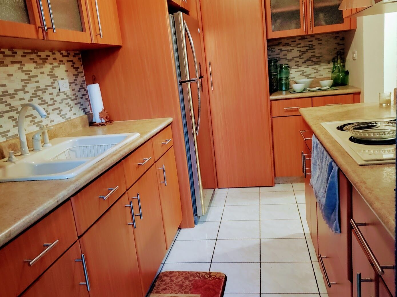 A kitchen with wooden cabinets, a stainless steel refrigerator, a sink, and a stove.