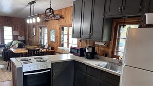 A kitchen with a stove, microwave, and refrigerator. There are wooden cabinets and a window. - Big Sandy Lake.  Beautiful and Private!<br><br> (McGregor)
