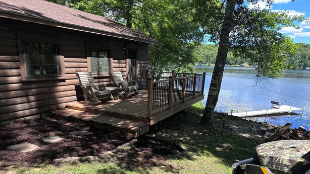A log cabin with a deck, outdoor seating, and a dock extending into a lake. - Big Sandy Lake.  Beautiful and Private!<br><br> (McGregor)
