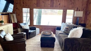 A cozy living room with wooden walls, a leather armchair, a sofa, and a television. - Big Sandy Lake.  Beautiful and Private!<br><br> (McGregor)