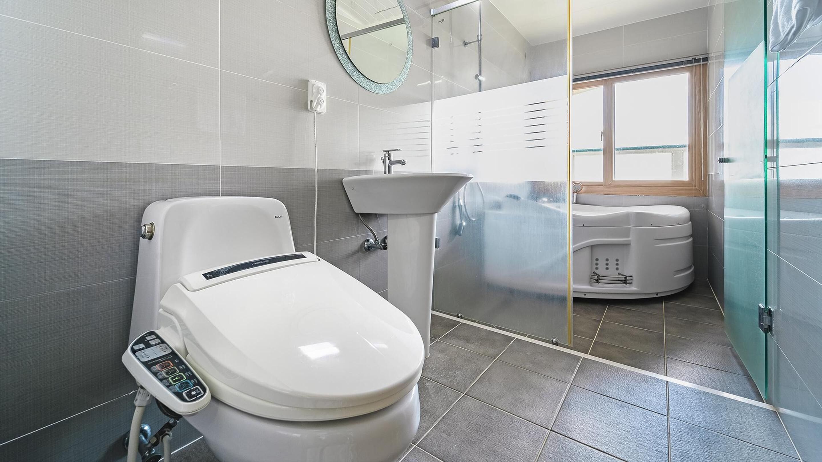 Un baño moderno con inodoro, lavamanos y cabina de ducha con mampara de vidrio.