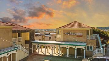 A hotel with a covered outdoor area, a sign reading "The Ocean Hill," and a view of the surrounding landscape.