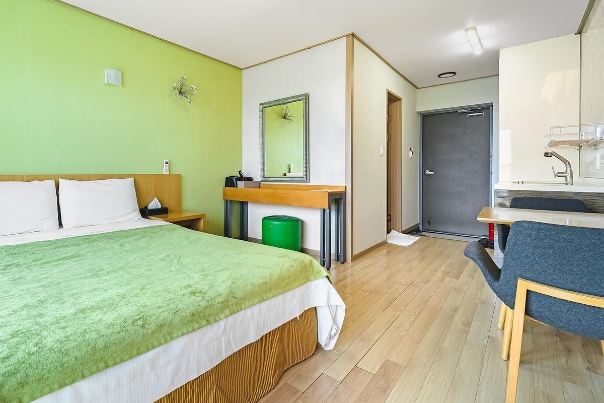 Une chambre d’hôtel équipée d’un lit, d’une table de chevet, d’un miroir et d’un coin cuisine.