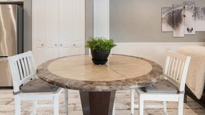 Una mesa de comedor redonda con una planta en maceta en el centro, rodeada de sillas blancas.