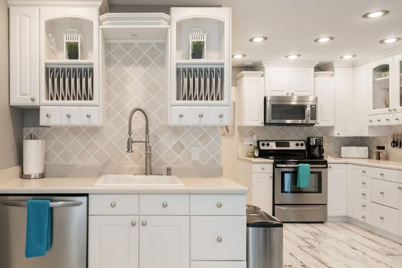 Une cuisine moderne avec des meubles blancs, un évier en acier inoxydable, un four à micro-ondes encastré et une cuisinière.