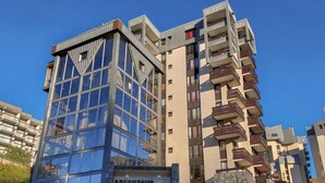 Un moderno edificio de apartamentos con fachada de vidrio y varios balcones.