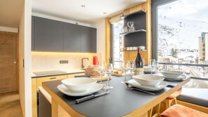 Una cocina moderna con una isla central, armarios de madera y vistas a un paisaje nevado a través de un ventanal amplio.