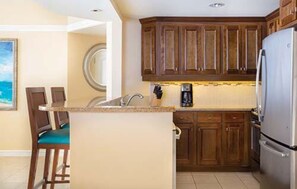 Compact kitchen with refrigerator, sink, and coffee maker.