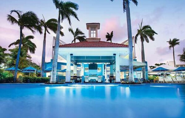 Relax by the pool surrounded by palm trees and lounge under the shade of a red-tiled roof.