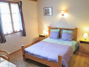 Ein Schlafzimmer mit einem hölzernen Bett, zwei Nachttischlampen, einem Nachttisch und einem Fenster mit Vorhängen.