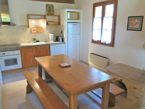 Eine Küche mit Holzausstattung, einem weißen Kühlschrank, einem Holztisch und einer Bank.