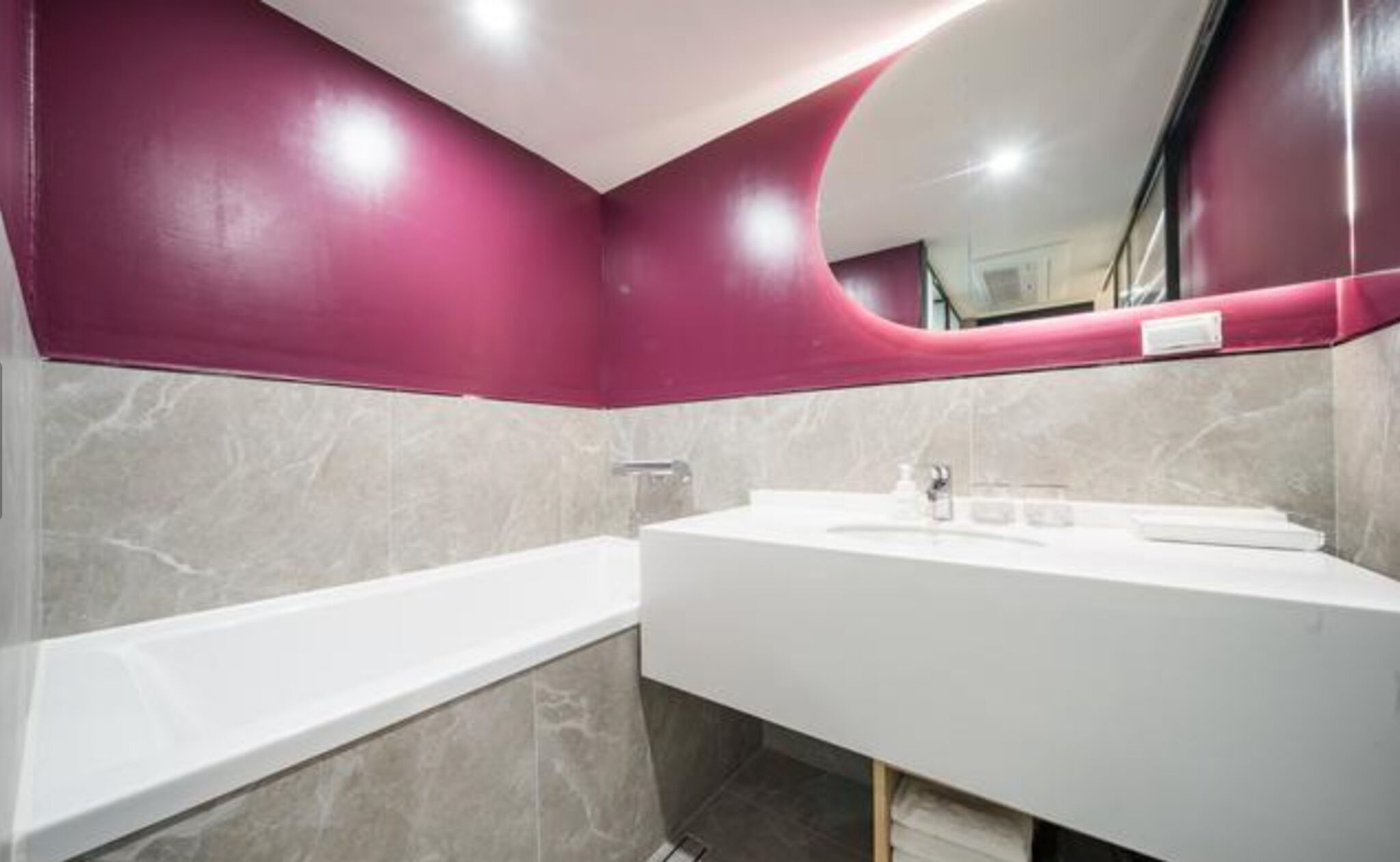 Un baño moderno con lavamanos blanco, un espejo y una bañera.
