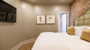 Ein Hotelzimmer mit einem großen Bett, einer Ziegelwand und zwei gerahmten Kunstwerken an der Wand.