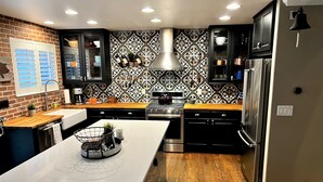 A modern kitchen with a central island, black cabinets, and a patterned backsplash. - Fully Remodeled Home In Boulder County (Superior)