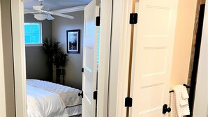 A bedroom with a bed, a ceiling fan, a window, and a door with a towel rack. - Fully Remodeled Home In Boulder County (Superior)