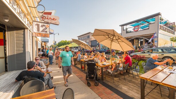 An outdoor dining area with tables and umbrellas, surrounded by buildings with various signs and storefronts. - Fully Remodeled Home In Boulder County (Superior)