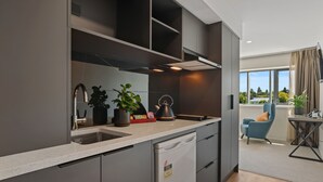 A modern kitchen with grey cabinetry, a dishwasher, and a kettle on the counter. - Golden Hotel (Christchurch)