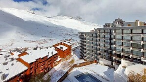 Een hotel met een modern design, met een combinatie van glazen en houten gevels, gelegen voor een besneeuwd berglandschap.