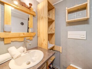 Une salle de bain avec un meuble-lavabo en bois, un évier et un miroir.