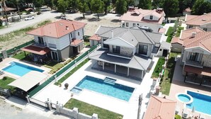 A residential area with multiple houses, a large central swimming pool, and a smaller pool to the right.