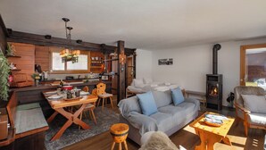 A cozy living room with a sofa, a dining table, and a fireplace. - SnowKaya Grindelwald by Interhome (Grindelwald)