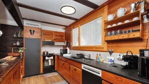 A kitchen with wooden cabinets, a dishwasher, a sink, and a window with a view. - SnowKaya Grindelwald by Interhome (Grindelwald)