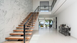 A modern interior with a wooden staircase, a high ceiling, and a view of the outdoors. - Onyx by Blue Sky Luxury (Weston)