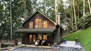 Un chalet rustique doté d’une véranda, entouré d’arbres.
