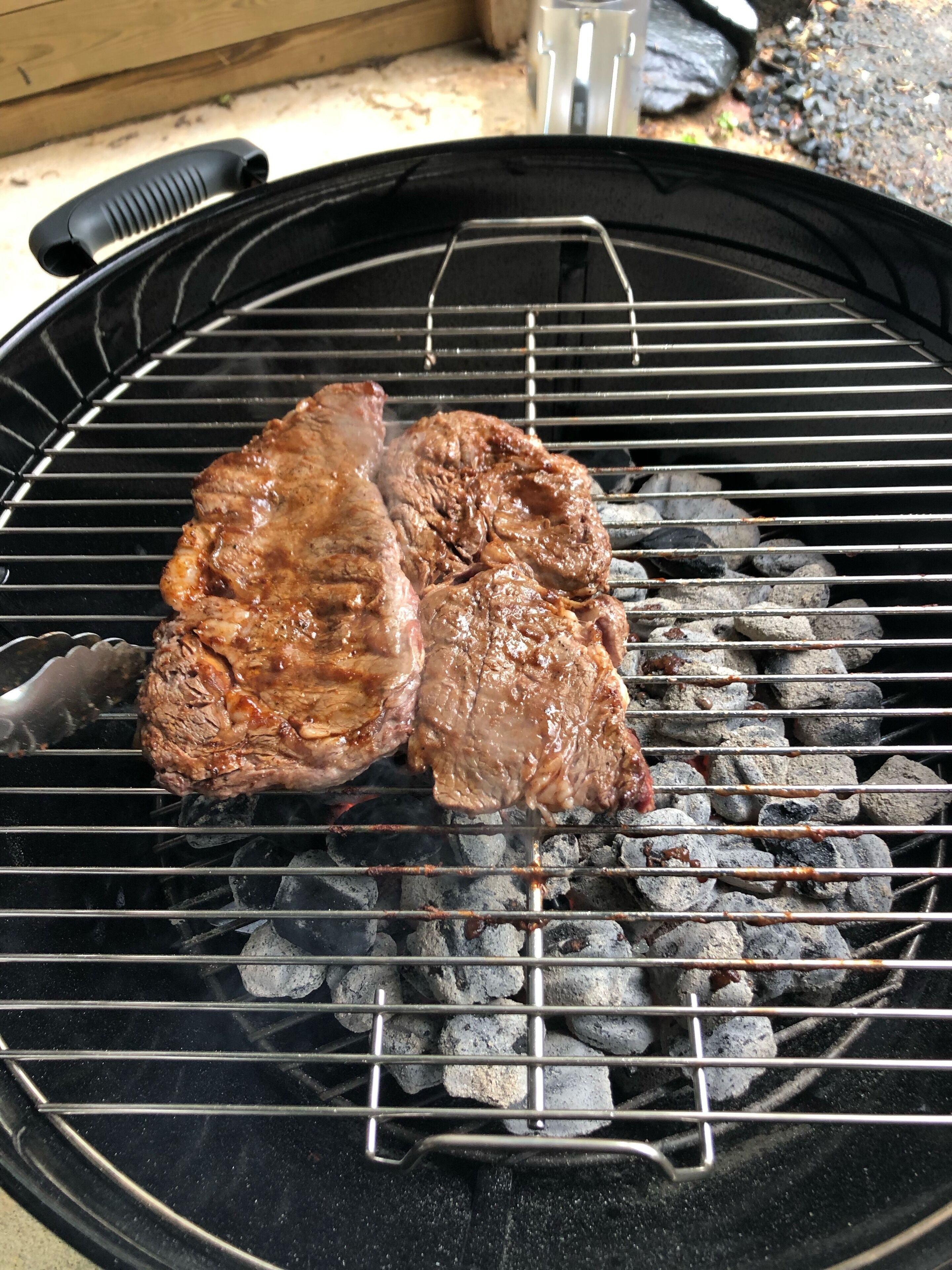 A grill with two steaks cooking over charcoal.