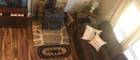 Un salon chaleureux avec une cheminée en pierre, un téléviseur, un canapé en cuir marron et un plancher en bois.