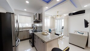 A modern kitchen with granite countertops, a stainless steel refrigerator, and a gas stove. - Luxurious 2BR condo with Rooftop, jacuzzi and BBQ (Santo Domingo)