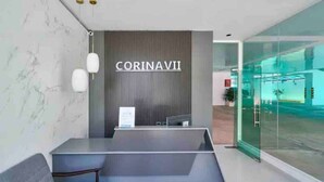 A reception area with a modern design, featuring a marble wall, a seating area, and a glass partition. - Luxurious 2BR condo with Rooftop, jacuzzi and BBQ (Santo Domingo)