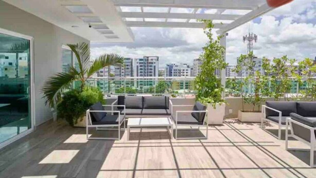 A rooftop terrace with a pergola, outdoor seating, and potted plants. - Luxurious 2BR condo with Rooftop, jacuzzi and BBQ (Santo Domingo)